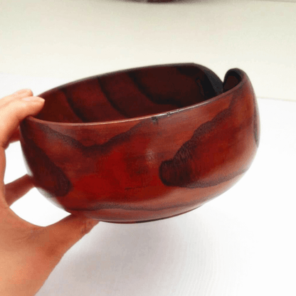 Handmade wooden crochet yarn bowl held in a hand, showcasing its unique grain and smooth finish.