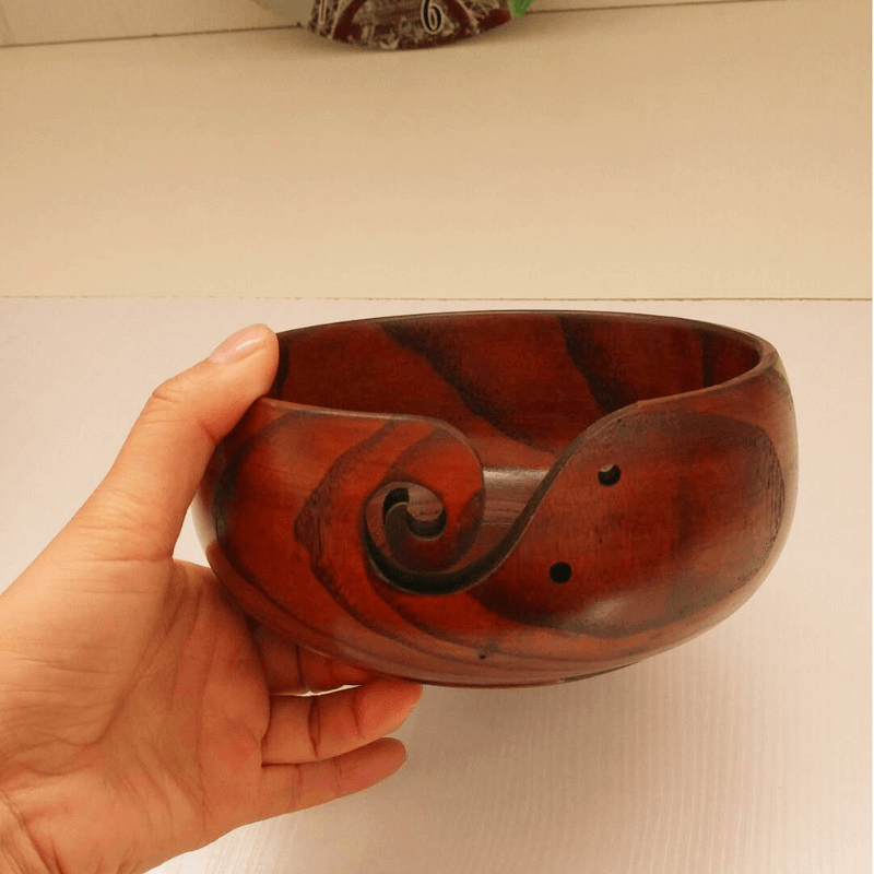 Handcrafted wooden crochet yarn bowl held in hand, featuring a smooth finish and elegant swirl design.