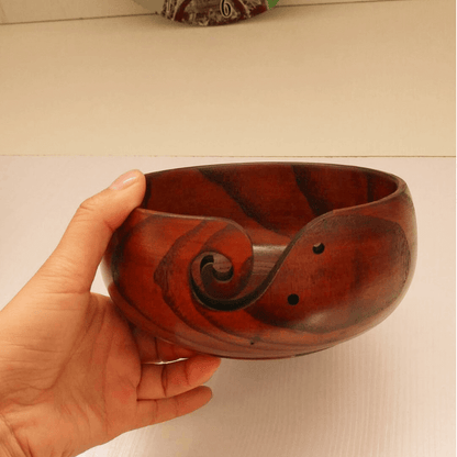 Handcrafted wooden crochet yarn bowl held in hand, featuring a smooth finish and elegant swirl design.