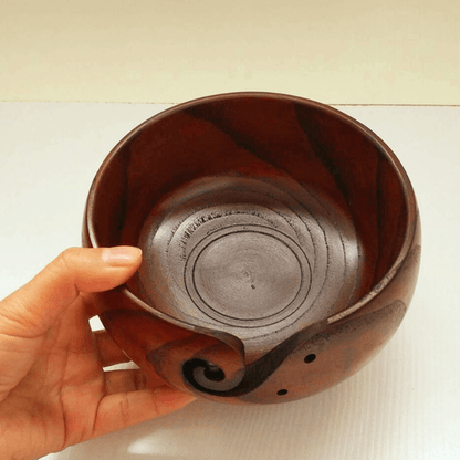 Handmade wooden crochet yarn bowl held by a hand, showcasing its smooth, artistic design.