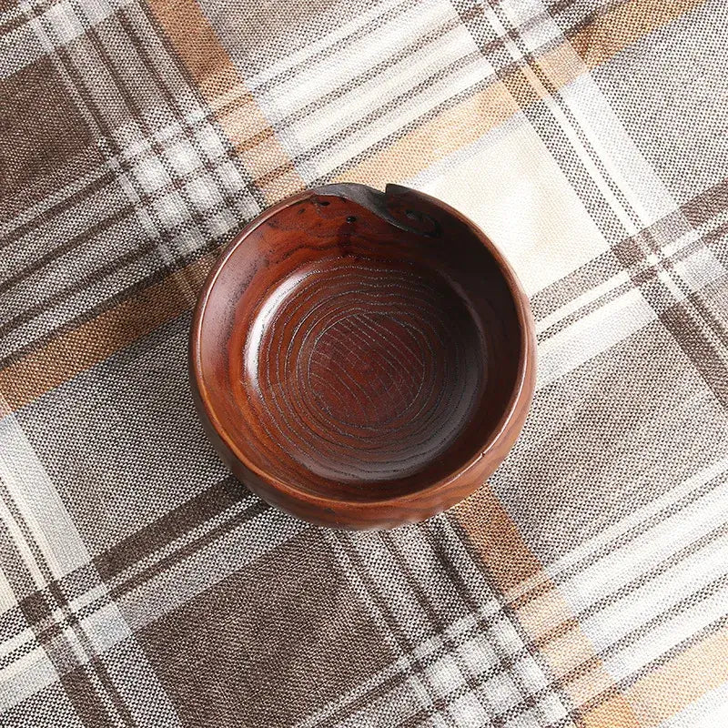 Handmade wooden crochet yarn bowl resting on a plaid backdrop, showcasing artisanal craftsmanship.
