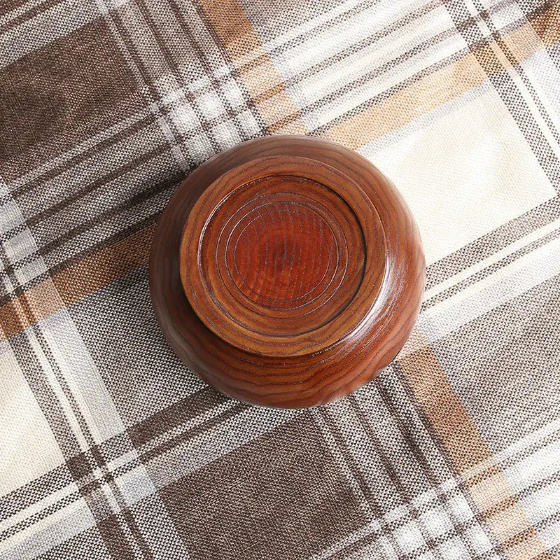 Handmade wooden crochet yarn bowl on a checkered fabric surface.