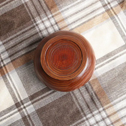 Handmade wooden crochet yarn bowl on a checkered fabric surface.