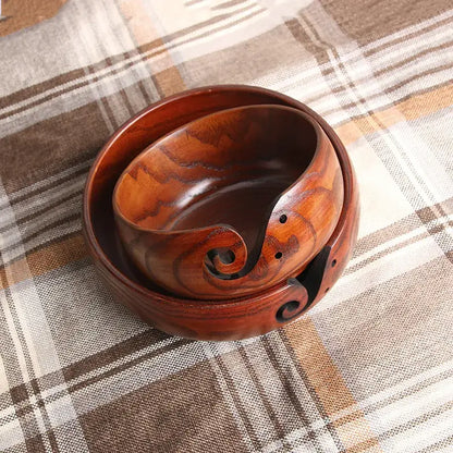 Two handcrafted wooden crochet yarn bowls with elegant curved designs, displayed on a checkered tablecloth.