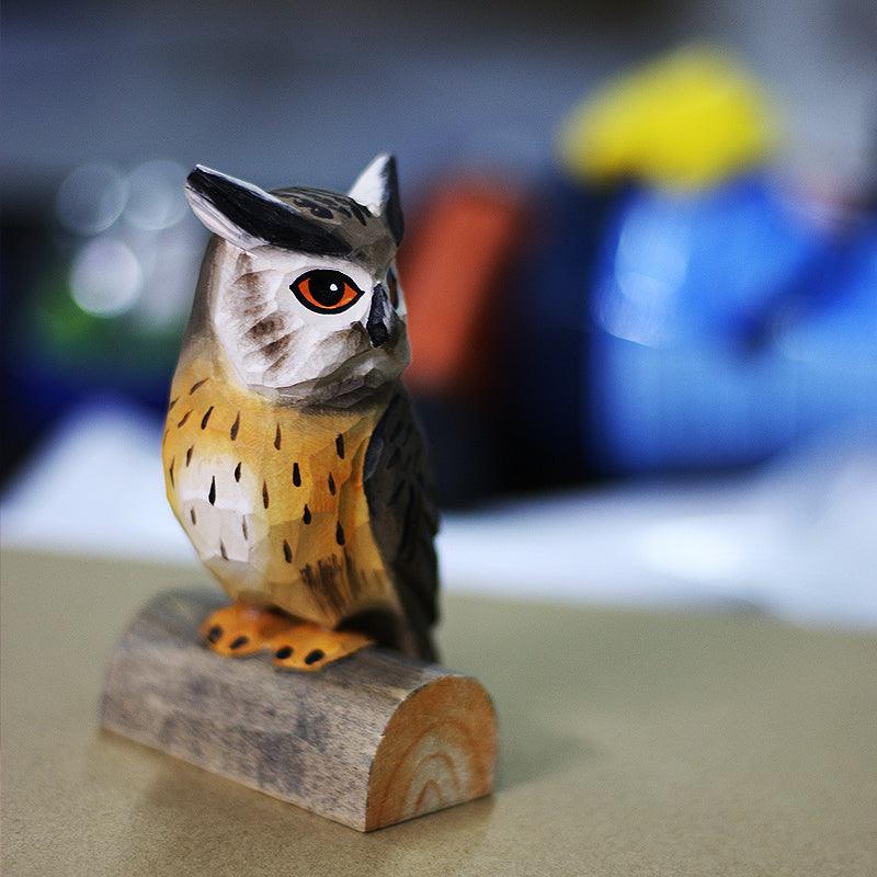 Hand carved northern white faced owl ornament sits perched on a small wood log.