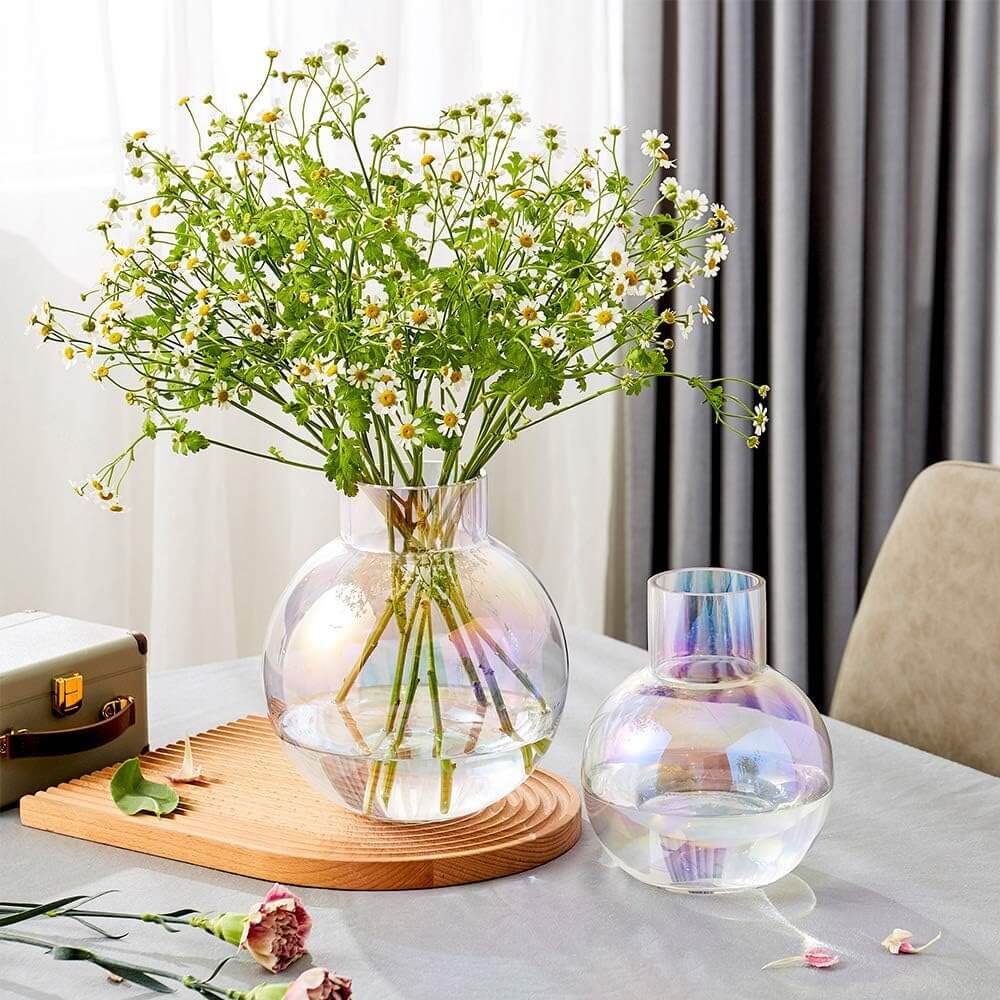Iridescent colour-shifting glass vases with fresh flowers on a rustic table setting.