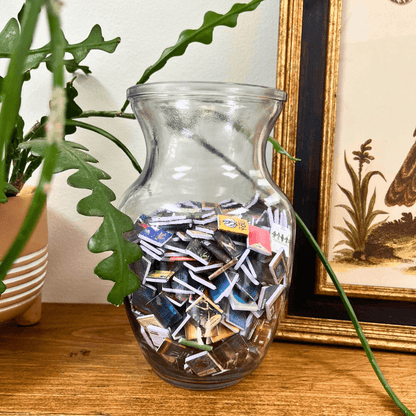 A clear vase filled with the mini books that come with the anxiety bookshelf.
