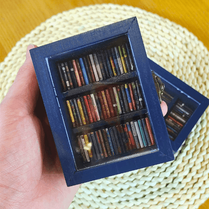 The Pocket Anxiety Bookshelf is held close to the camera for a close up view of the tardis blue paint and miniature books.