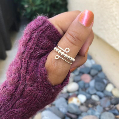 Adjustable size fidget ring displayed on a females thumb.