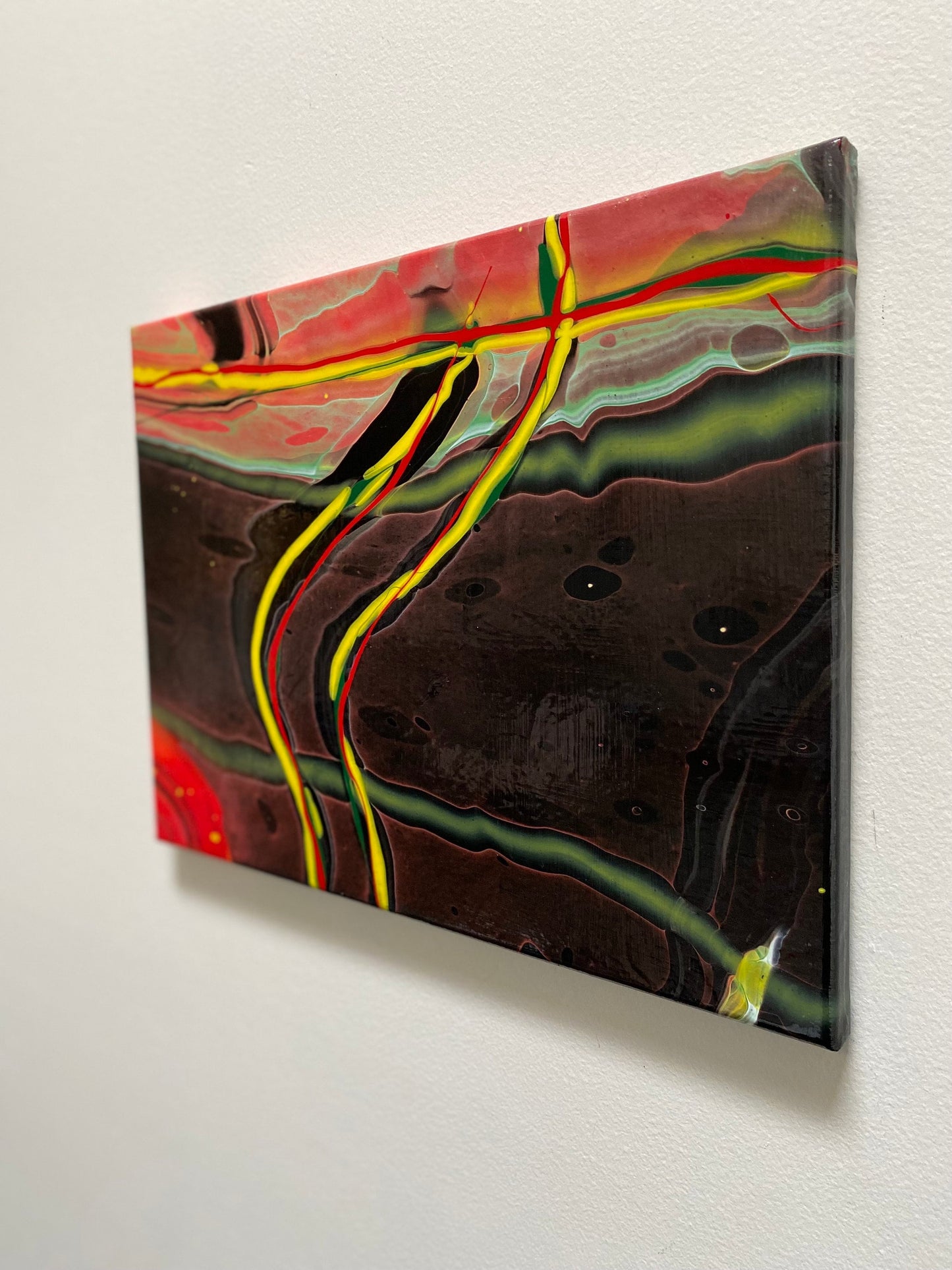 abstract fluid art featuring a black background, with yellow, red and green flowing lines